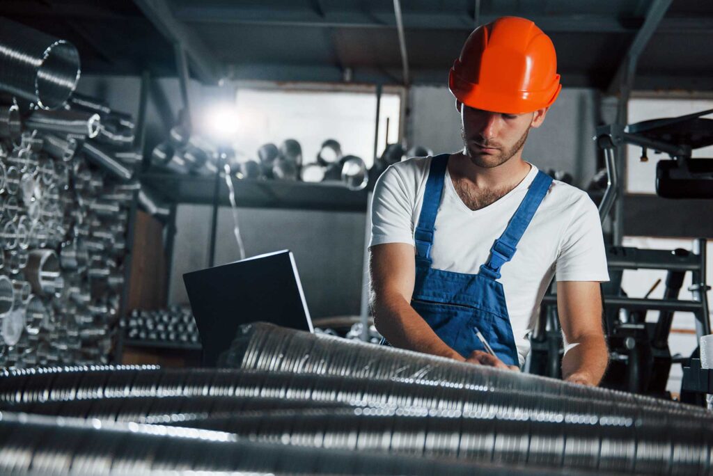 A young man in industrial uniform concentrated at work
