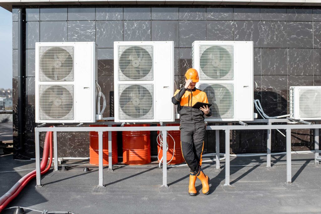 A workman next to four air conditioning units