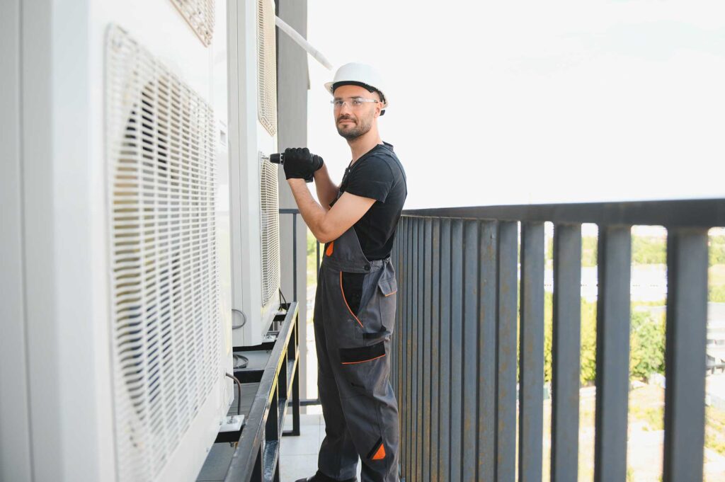 Young man repairman checking an outside air conditioner